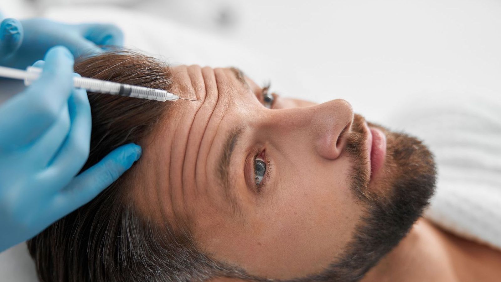 Man receiving a Botox injection in his forehead to soften horizontal lines