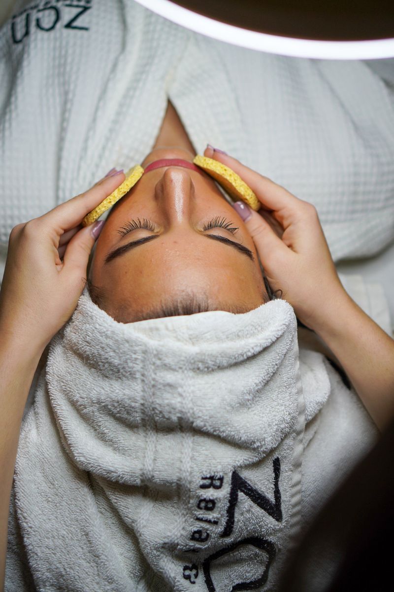 Woman relaxing with her hair wrapped in a towel while receiving a facial treatment