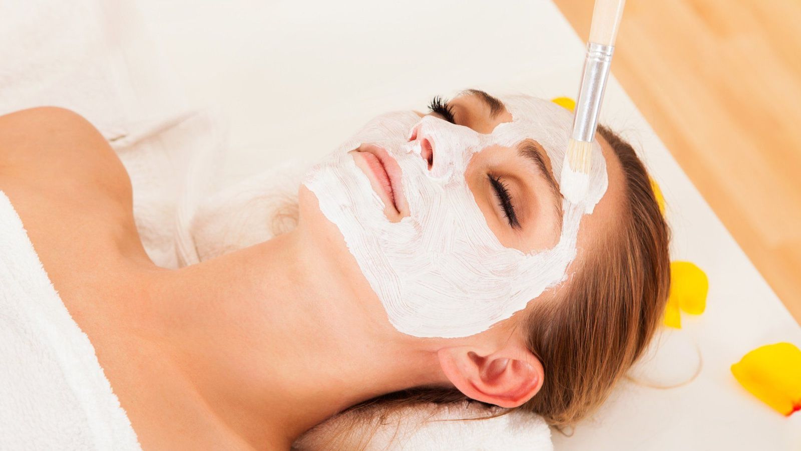 Woman relaxing with eyes closed while a skincare treatment is applied to her face