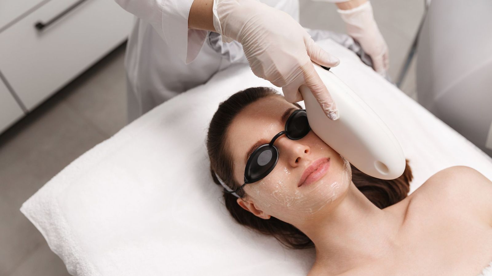 Woman wearing protective eyewear during a laser hair removal treatment on her face